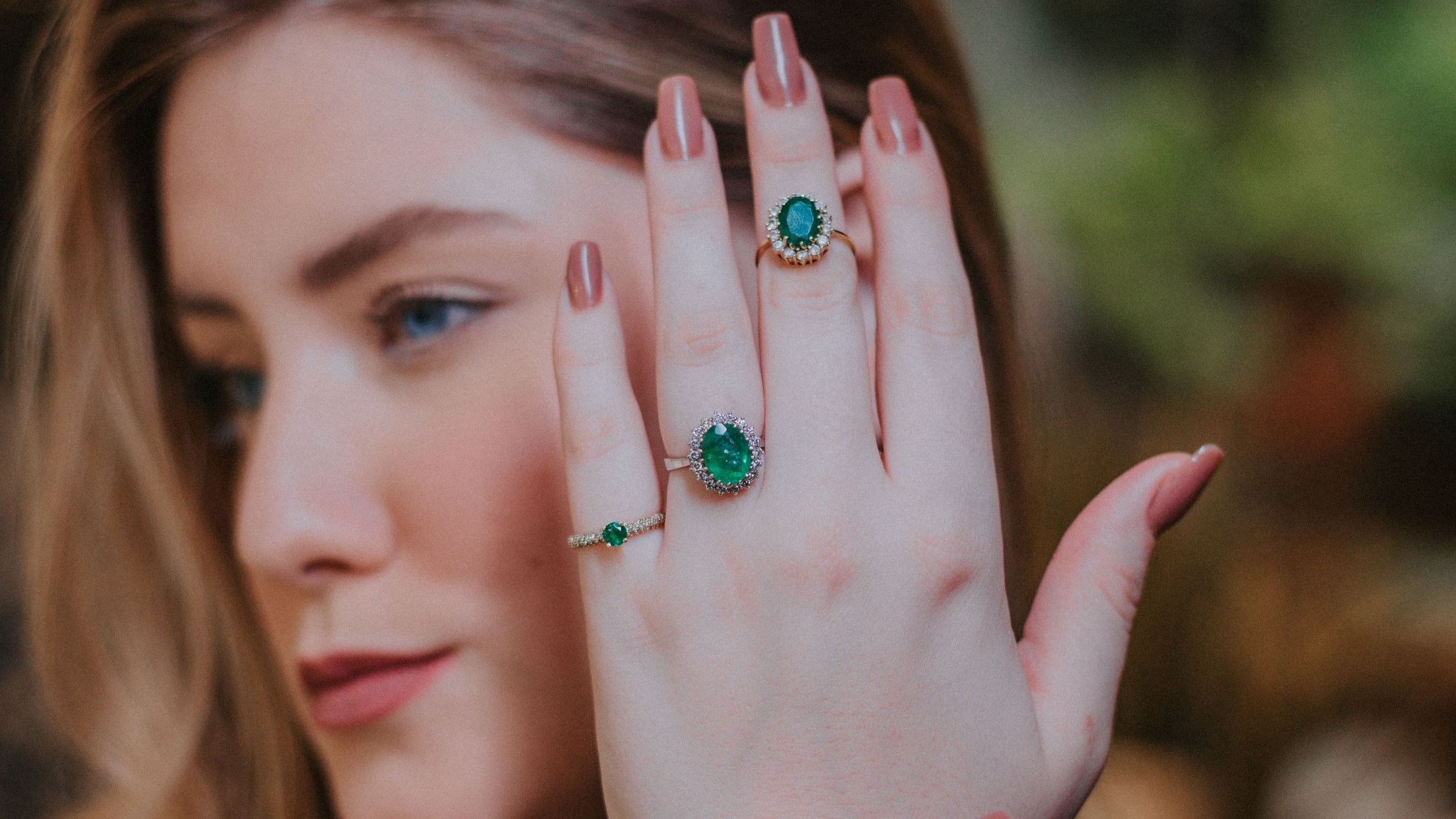 hermosa mujer con joyas de esmeralda piedra preciosa natal de mayo. Preciosas rotijas de diamantes y esneraldas en sus dedos
